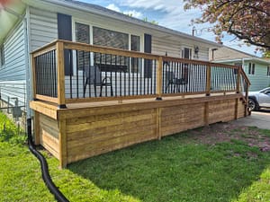 Cedar deck with black metal railing and skirting built onto the side of a house